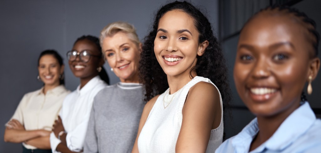 A diverse group of confident women smiling and looking at the camera, symbolizing empowerment, inclusion, and leadership in the tech industry.