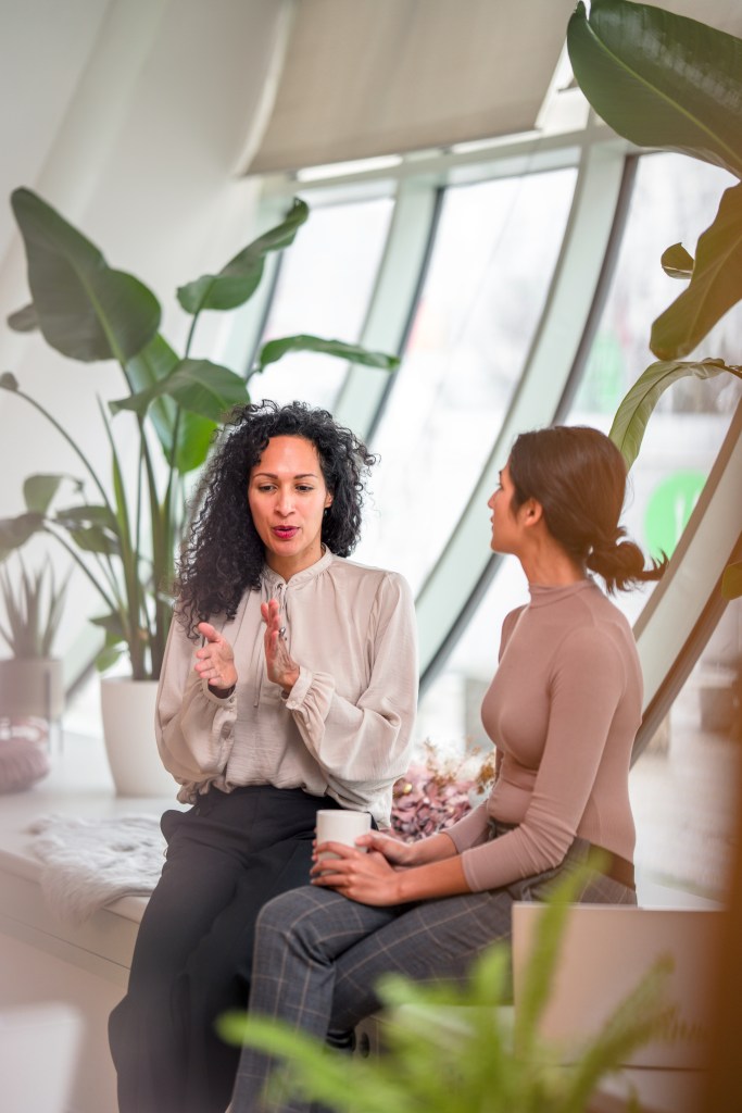 Two women engaged in dialogue, symbolizing mentorship, guidance, and meaningful connection in the tech industry.